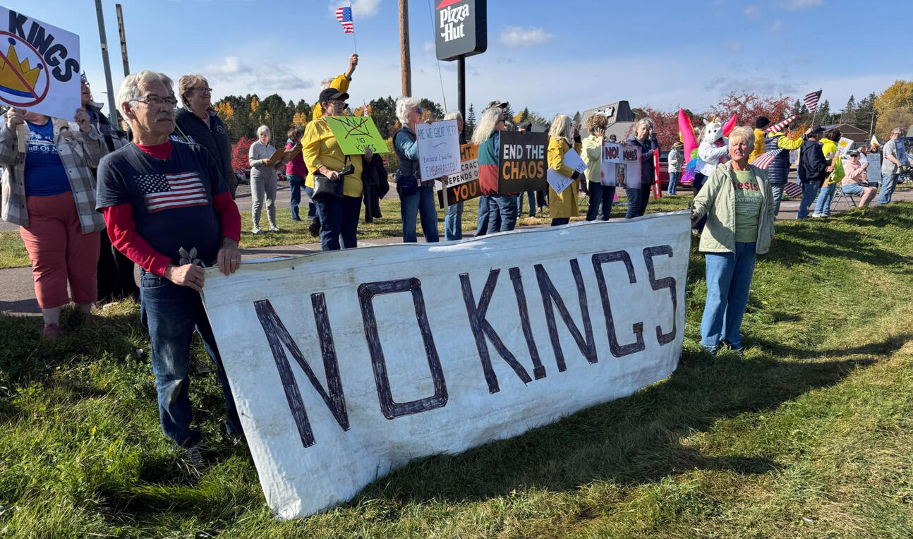 Protest participants holding advocacy signs during No Kings 2.0 demonstration in Cloquet, Minnesota